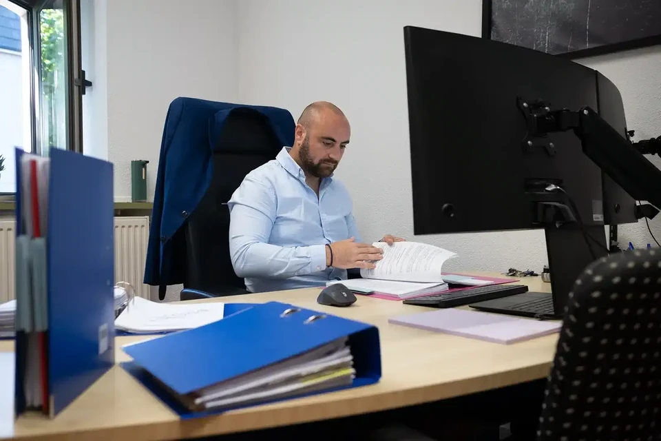 Femme travaillant sur documents financiers dans bureau moderne, utilisant calculatrice et stylo pour analyser des données comptables